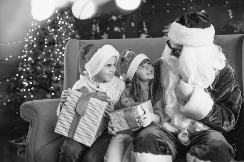 Groupe d'enfants assis avec le père noël et tenant des cadeaux