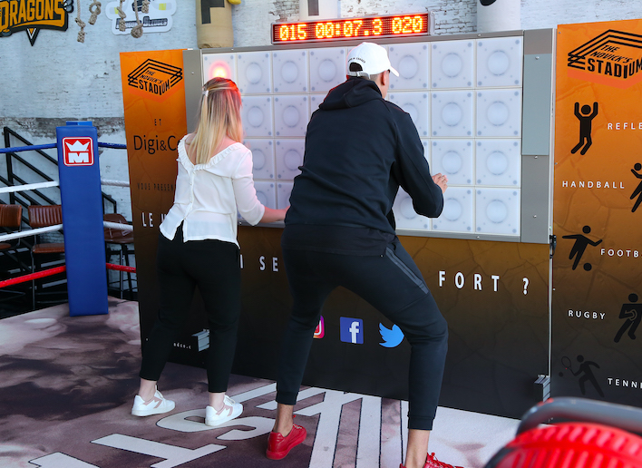 Deux personnes testant leurs réflexes sur le mur digital à l'image du Novick's Stadium