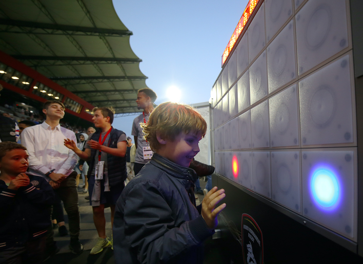 Jeune garçon jouant au mur digital dans les tribunes d'un stade