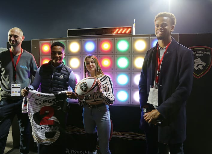 Quatre personnes posant devant de mur digital lors d'un match du Rouen Normandie Rugby