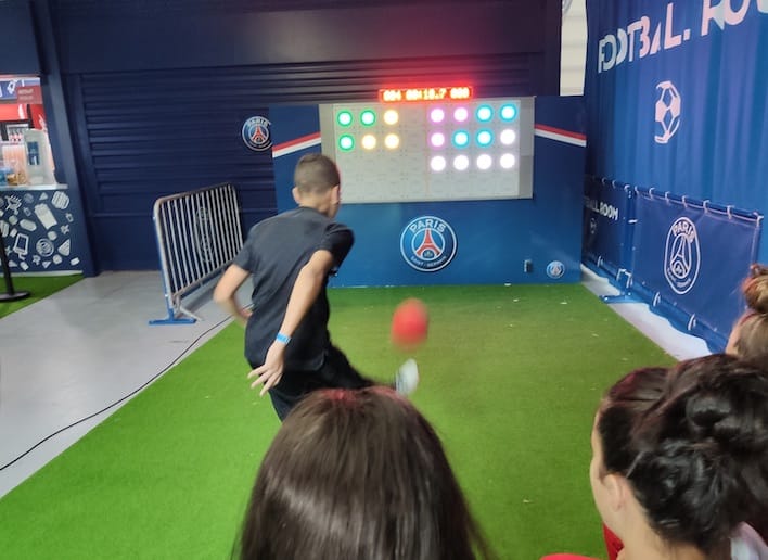 Garçon jouant au football face au mur digital lors d'un match du Paris Saint Germain