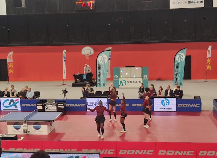 Groupe de danseuses dans un gymnase lors d'un match de tennis de table avec le mur digital en arrière plan